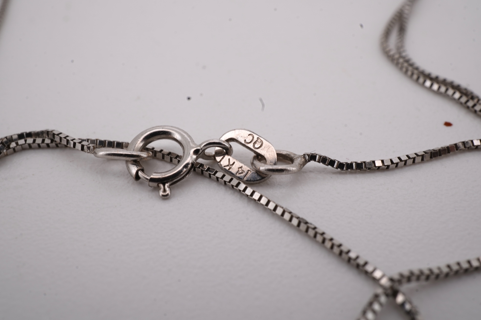 A prasiolite and diamond pendant, the diamond-set bail suspending a cushion-shaped chequerboard-cut prasiolite, to a fine link chain, mounted in 14ct gold, pendant length 2.5cm, chain length 46cm, British hallmarks, gros